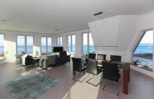 ein Wohnzimmer mit Tisch und Stühlen und Fenstern in der Unterkunft Appartement in Sellin mit Garten, Sauna und Terrasse und Meerblick in Ostseebad Sellin