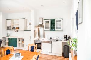 a kitchen with white cabinets and a wooden table at Villa Waldidyll in Braunlage +10 photos