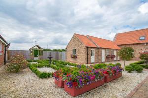 a garden with flowers in pots in front of a house at Meals Farm - Courtyard Room in North Somercotes