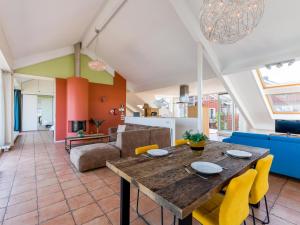 a living room with a wooden table and yellow chairs at Penthouse in Uitgeest