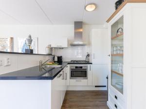 a kitchen with white cabinets and a sink at Appartement Assum I in Uitgeest
