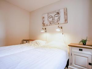 a bedroom with a white bed and two lamps at Appartement Assum I in Uitgeest