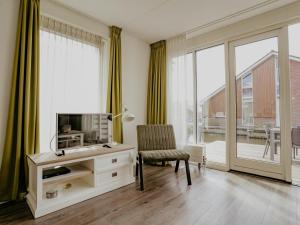 a living room with a tv and a chair at Appartement Assum I in Uitgeest