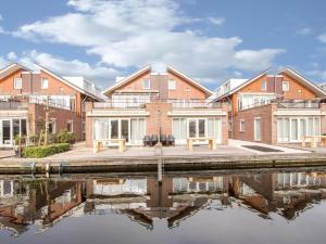 an apartment building with a reflection in the water at Appartement Assum I in Uitgeest
