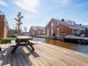 a wooden deck with a picnic table and a boat at Waterfront in Uitgeest