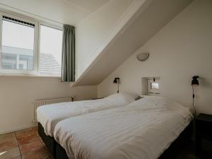 two beds in a room with a window at Oostergeest in Uitgeest