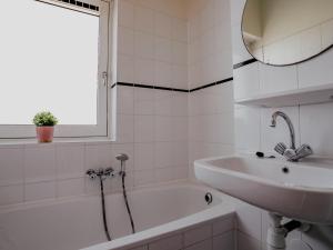a white bathroom with a sink and a bath tub at Busch en Dam in Uitgeest