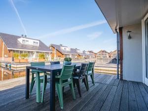 a table and chairs on a deck with a view of houses at Busch en Dam in Uitgeest