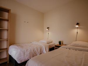 two beds in a room with white sheets at Waterbase in Uitgeest
