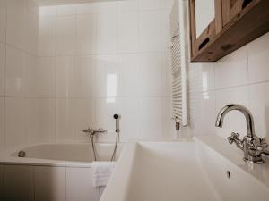 a white bathroom with a sink and a bath tub at Waterbase in Uitgeest +14 photos