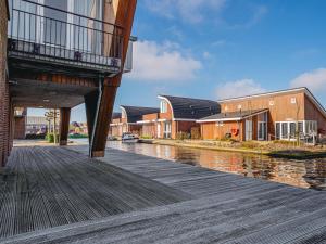 a wooden walkway next to a river with buildings at Waterbase in Uitgeest