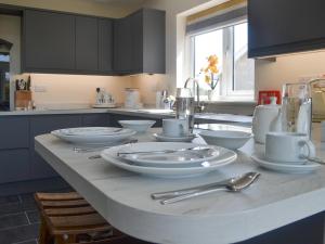 a kitchen with white plates and silverware on a counter at Benlli in Aberdaron +13 photos