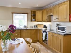 a kitchen with wooden cabinets and a table with a vase of flowers at Ferguson in Warenford