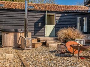 une petite maison avec une porte et un grill dans l'établissement The Butterchurn - Uk50805, à Cratfield 1 autre photo