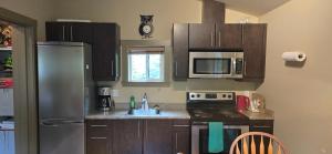 Una cocina con gabinetes de madera y un refrigerador de acero inoxidable. en A Shack In The Woods, en Port Renfrew 79 fotos más