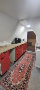 une cuisine mansardée avec des placards rouges et un tapis dans l'établissement Lily Apartment, à Tromsø