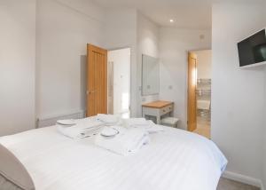 PorkellisCaddys Corner Lodges的一间白色的卧室，床上有一条白色的毛巾