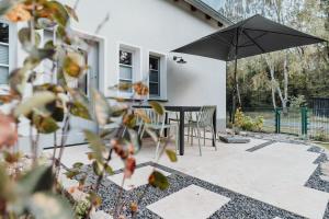 un patio avec un parasol, une table et des chaises dans l'établissement Spreewaldhaus Am Landgut Der Stall, à Markische Heide