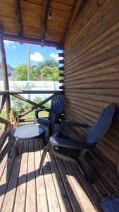 duas cadeiras e uma mesa em um deck de madeira em Cabañas Don Camilo em Tandil mais 1 fotografia