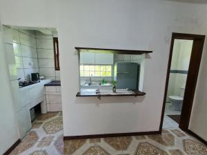 Una cocina blanca con fregadero y espejo. en Villa Pachamama Hospedaria - Praia do Rosa, en Praia do Rosa