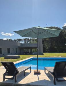 einen Pool mit 2 Stühlen und einem Sonnenschirm in der Unterkunft Hermosa Casa De Campo en Mercedes in Mercedes