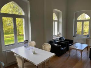 un salon avec une table, des chaises et des fenêtres dans l'établissement Weisses Traumschloss An Der Ostsee, à Hohendorf
