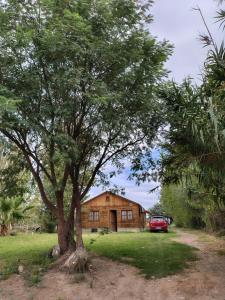 Cabaña El Maturrango的房子前面有一棵树，旁边停着一辆红色汽车。