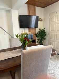 - un salon avec une table, une télévision et des fleurs dans l'établissement Alquiler en el CENTRO Luz, à Río Gallegos