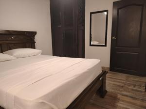 Acogedor Apto en el Rodadero في Gaira: غرفة نوم بسرير ابيض كبير وباب اسود