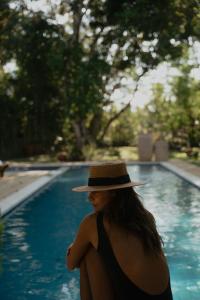 une femme portant un chapeau se tenant à côté d'une piscine dans l'établissement Villa Cacau - Floresta, à Trancoso