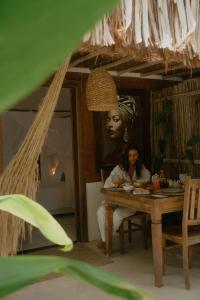 une femme assise à une table dans une pièce dans l'établissement Villa Cacau - Floresta, à Trancoso 134 autres photos
