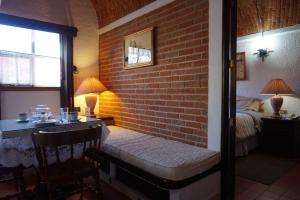eine Bank in einem Zimmer mit Ziegelwand in der Unterkunft Suites Poza Real in Tequisquiapan