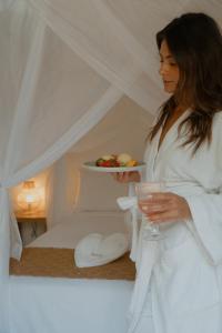 a woman in a white robe holding a plate of food at Villa Cacau - Floresta in Trancoso