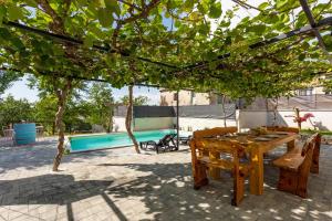une terrasse avec une table et des chaises en bois ainsi qu'une piscine dans l'établissement Schönes Ferienhaus In Modrusani Mit Großem Garten, à Žminj