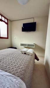 une chambre avec un lit et une télévision au mur dans l'établissement Habitación privada en el centro de la ciudad, à Ayacucho