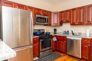 een keuken met houten kasten en een roestvrijstalen koelkast bij CityStay in Baltimore +9 foto's