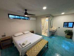 a bedroom with a white bed and a bathroom at La punta surfhouse 2 in Puerto Escondido