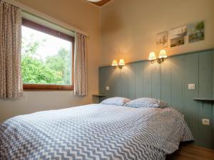 a bedroom with a bed with a blue and white comforter at Rustic Retreat in Houvegné in Houvegné