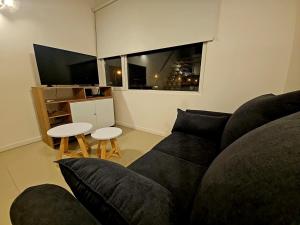 a living room with a black couch and a table at Departamento Studio 20 - Rio Grande - Tierra del Fuego in Río Grande +6 photos