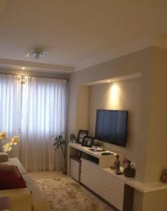 a living room with a flat screen tv on a wall at Quarto com ar condicionado tv para uma pessoa in Passo Fundo