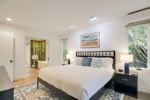 a white bedroom with a large bed and two lamps at Casa Playa in Santa Barbara