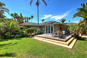 a house with a deck with a table and chairs at Little Palm Cottage in Santa Barbara