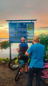 une femme et un homme à vélo devant un panneau dans l'établissement Villaggio Homey, à Munroe Island