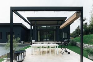 ein schwarzes Haus mit weißen Tischen und Stühlen auf einer Terrasse in der Unterkunft Laf Denen 千葉県富津市のvacation rental in Futtsu