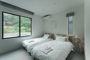 zwei Betten in einem Zimmer mit zwei Fenstern in der Unterkunft Laf Denen 千葉県富津市のvacation rental in Futtsu