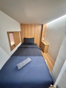 a large blue bed in a small room at Althia Capsule Quarters in Badung