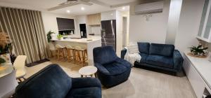 sala de estar con 2 sillas azules y cocina en Cerulean Apartments, en Caloundra