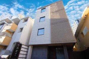 ein hohes Gebäude mit einem Gebäude in der Unterkunft HOTEL YeeT Tenjin Minami in Fukuoka