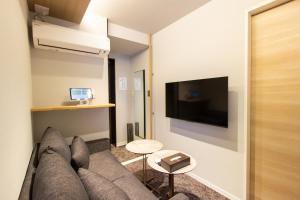 ein Wohnzimmer mit Sofa und Flachbildfernseher in der Unterkunft HOTEL YeeT Tenjin Minami in Fukuoka