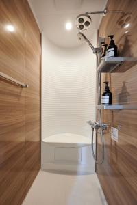 a shower in a bathroom with wooden walls at なぎさホテル in Zushi